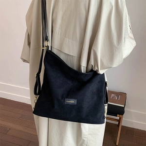 Close-up of matte black bucket bag with a FASHION label and golden metal hardware details