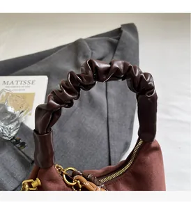 Detail of coffee brown suede dumpling bag with stylish ruched leather top handle