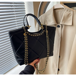 Detail of black quilted leather tote bag with gold chain strap and zipper closure