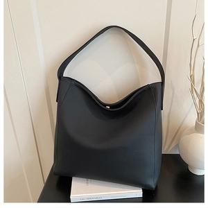 Macro view of black matte leather tote bag featuring a silver magnetic clasp and clean seams