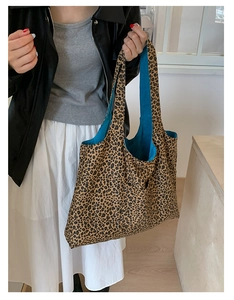 Leopard print tote bag with vibrant blue lining shown on a shoulder in a lifestyle shot