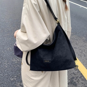 Detail of matte black bucket bag with gold hardware and fashion metal plate