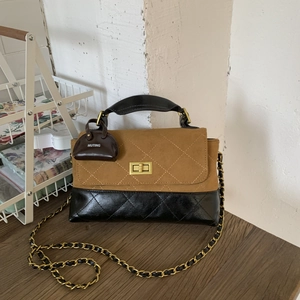 Detailed macro view of vintage contrast quilting and gold metal twist lock on square bag