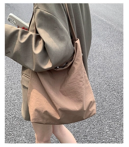 Détail du sac cabas en nylon kaki à texture plissée porté à l'épaule par un mannequin