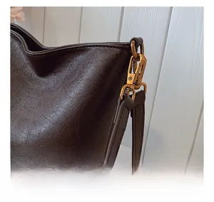 Gros plan du sac seau en cuir grainé marron avec des détails de quincaillerie dorée