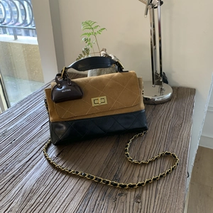 Detail of color-block flap bag featuring diamond quilting, gold twist lock and chain strap