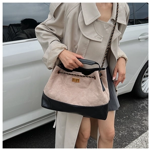 Close-up of beige quilted suede and black leather tote bag with gold twist lock