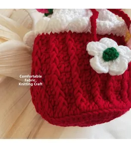 Close-up of handmade knit bucket bag with floral accents and textured red yarn details