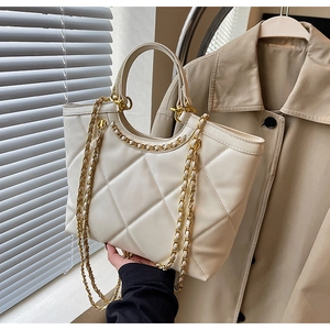Close-up of cream quilted tote bag with gold chain strap and elegant round handles
