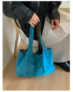 Detail of blue suede tote bag with leopard print lining and front pocket on a model