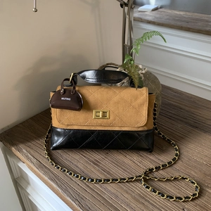 Close-up of quilted two-tone crossbody bag featuring golden hardware and chain strap