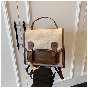 Detail of vintage canvas backpack featuring brown leather trim and dual buckle closures