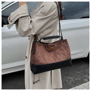 Detail of vintage quilted tote bag with brown suede patchwork and gold twist-lock closure