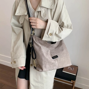 Close-up of matte grey bucket bag with drawstring design and black fashion label