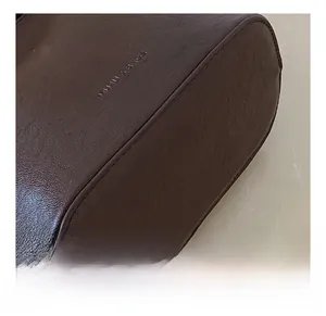 Gros plan du sac seau en cuir marron avec logo de la marque et détails de couture