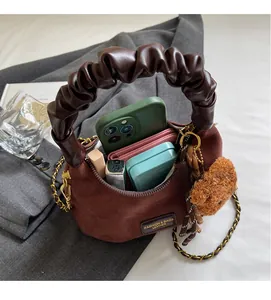 Detail of brown suede hobo bag interior with phone and lipstick on grey suit fabric