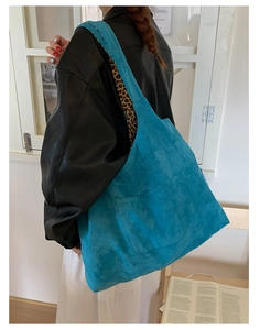Close-up of sky blue corduroy tote bag featuring wide shoulder straps and side brand label