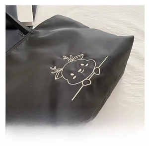 Detail shot of white cartoon deer embroidery on black canvas tote bag showing stitching quality