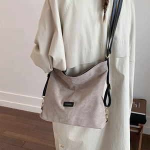 Detail view of khaki suede tote bag with black adjustable strap and fashion label detail