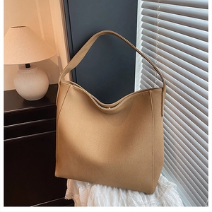 Detail of camel brown large capacity tote bag with wide strap on minimalist background