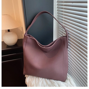 Detail view of large mauve faux leather tote bag on white cloth with warm lighting