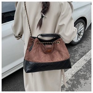 Street style shot of the vintage brown suede and black leather quilted tote bag worn by model