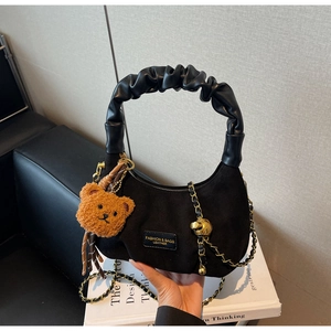 Close-up of black hobo bag with teddy charm, leather handle and gold chain detail