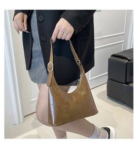 Detail of vintage brown crescent bag with retro oil leather texture and gold metal buckle