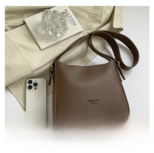 Bolso Hobo de cuero marrón con texto fashion bag NEW YORK sobre fondo de gabardina beige