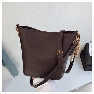 Vue détaillée du sac seau en cuir marron montrant le grain du cuir et le bijou de sac
