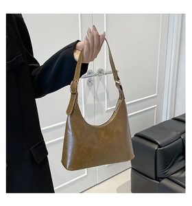Detail of vintage brown faux leather hobo bag with adjustable strap and silver metal buckle