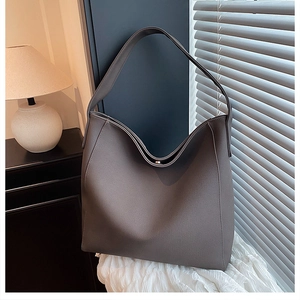 Macro shot of large dark grey tote bag on white textured cloth in minimalist home setting