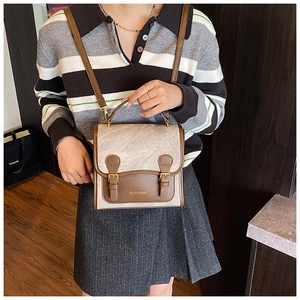 Close-up of vintage pebble-grain flap and brown leather handles on a crossbody backpack