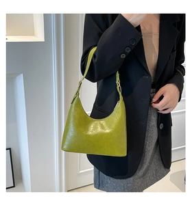 Close-up of a bright green leather hobo bag worn over the shoulder with a black blazer