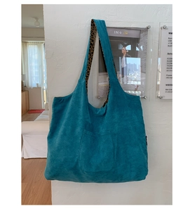 Detail of lake blue corduroy tote bag with leopard print handles and side brand label