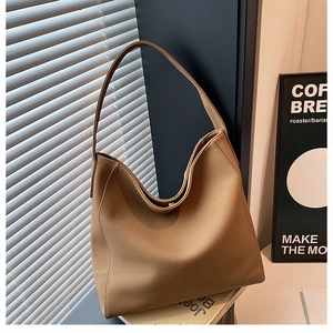 Detail of a brown leather tote bag with soft matte texture and seamless wide shoulder strap