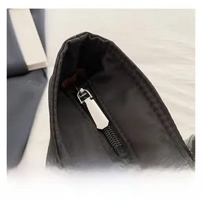 Detail of smooth silver metal zipper and precise stitching on black nylon tote bag