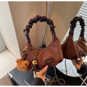 Brown suede hobo bag with pleated handle, gold chain strap, and cute bear charm detail
