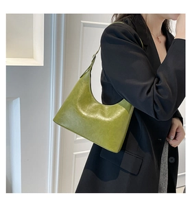 Model wearing vintage green hobo bag in glossy PU leather with adjustable shoulder strap