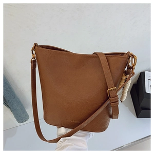 Détail du sac seau marron vintage avec logo MUJU BAGS et breloque en perles de bois