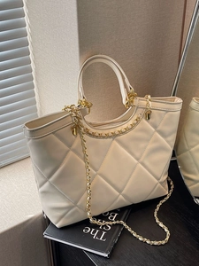 Beige quilted tote bag with diamond pattern and gold chain strap in natural lighting