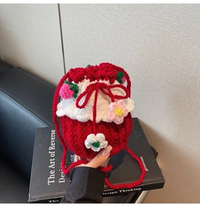 Detail of handmade crochet bucket bag with red knit flowers and strawberry charms