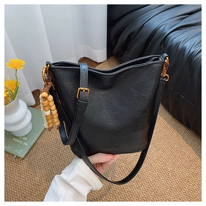 Détail du sac seau noir vintage avec ferrures dorées et perles décoratives en bois