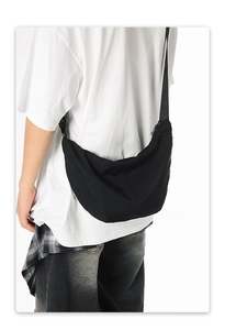 Rear view of a model wearing the large black nylon crescent crossbody bag in a studio