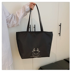 Close-up of black canvas tote bag with golden reindeer embroidery and long shoulder straps