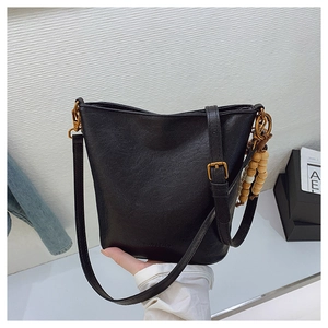 Détail du sac seau noir avec breloque en perles de bois et boucle en bronze