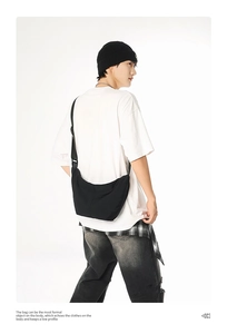 Side view of a black nylon crescent crossbody bag worn by a male model for outdoor use