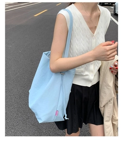 Grand sac cabas en toile bleu clair avec fermeture à cordon porté à l'épaule en ville