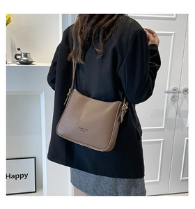 Brown leather hobo bucket bag with fringe detail and adjustable shoulder strap worn by model