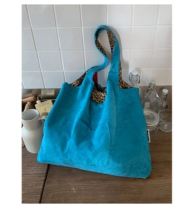 Close-up of blue corduroy tote bag with leopard print lining and Merci label detail